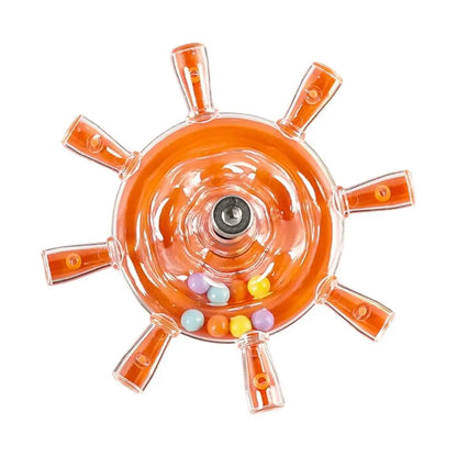 An orange transparent plastic wheel-shaped product with six radiating arms and a small cluster of pastel-colored round beads near the center, shown on a plain white background.