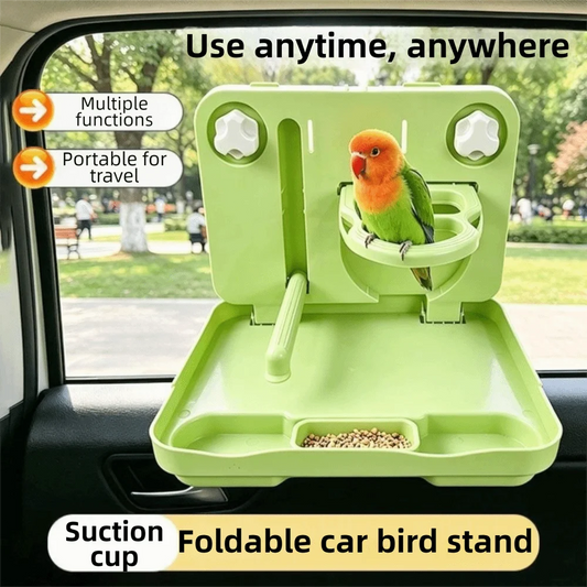 A light green foldable car bird stand with a suction cup attachment, shown mounted inside a car window. A small green and orange bird is perched on the stand, and birdseed is visible in the tray.